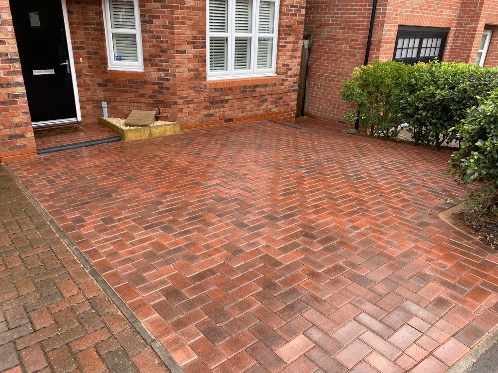 Herringbone block paved driveway wrapping around the front of a red brick house