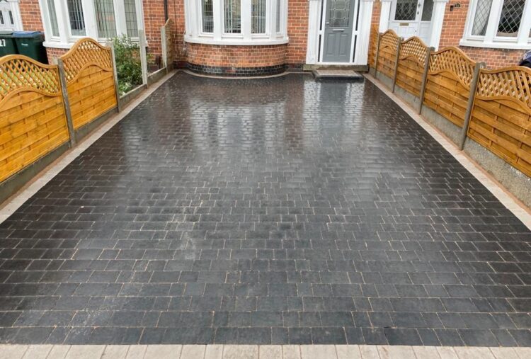 Charcoal block paved driveway laid between fenced boundaries