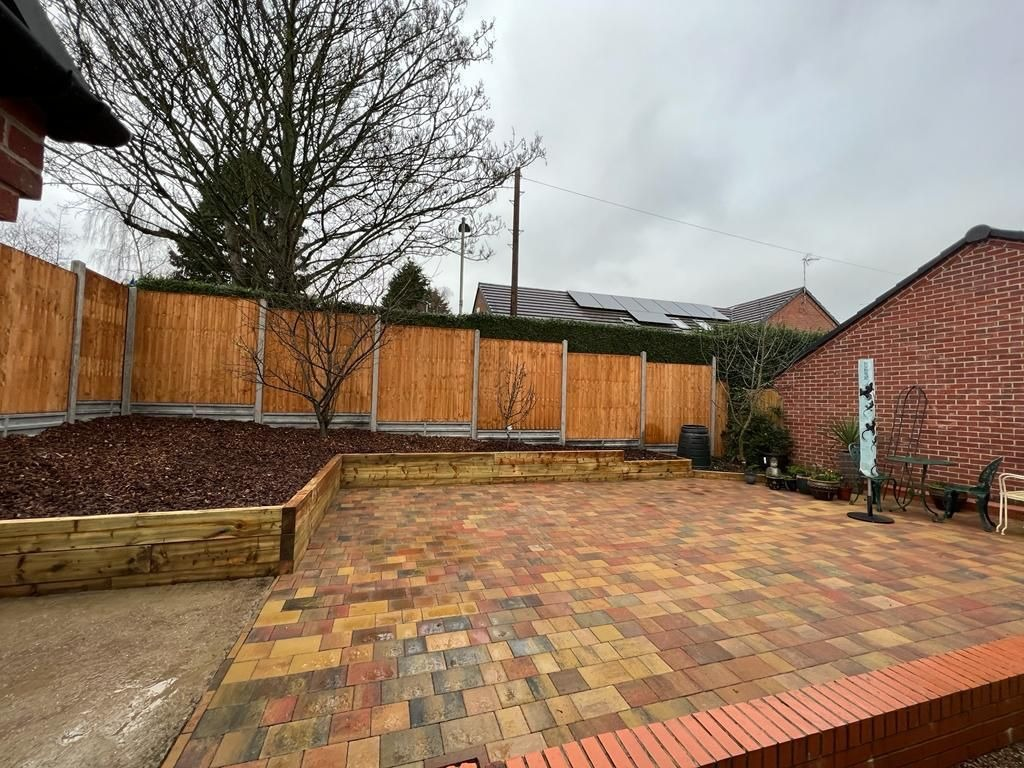 Block paved patio with sleeper raised beds and a brick border