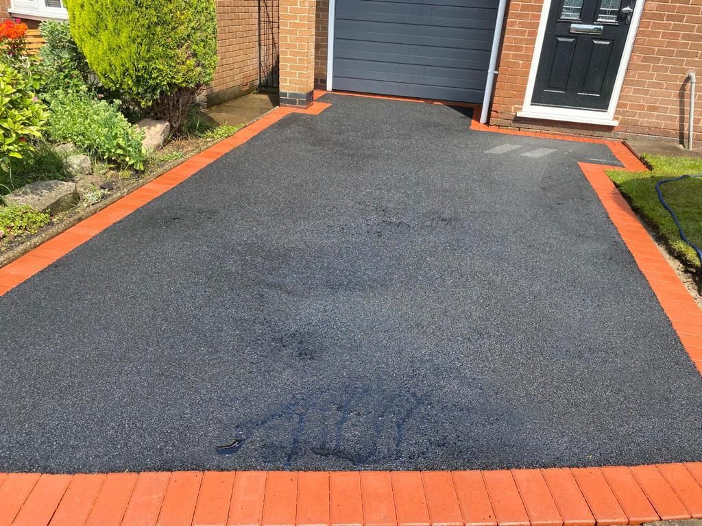 Tarmac driveway with a red brick border edge